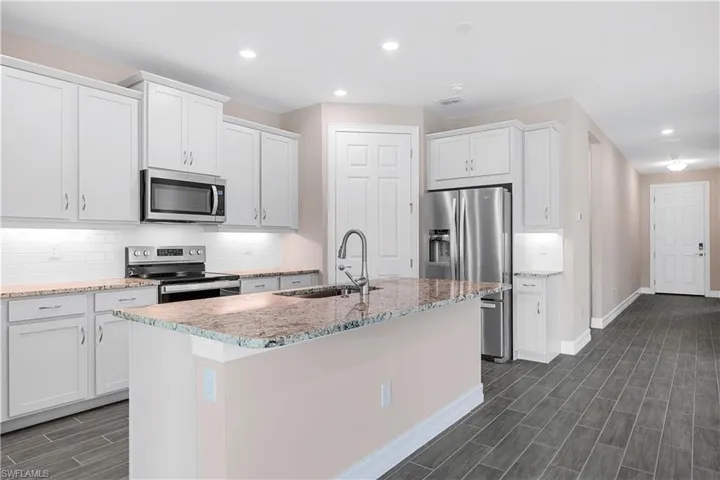 Kitchen with sink, stainless steel appliances, an island with sink, and backsplash