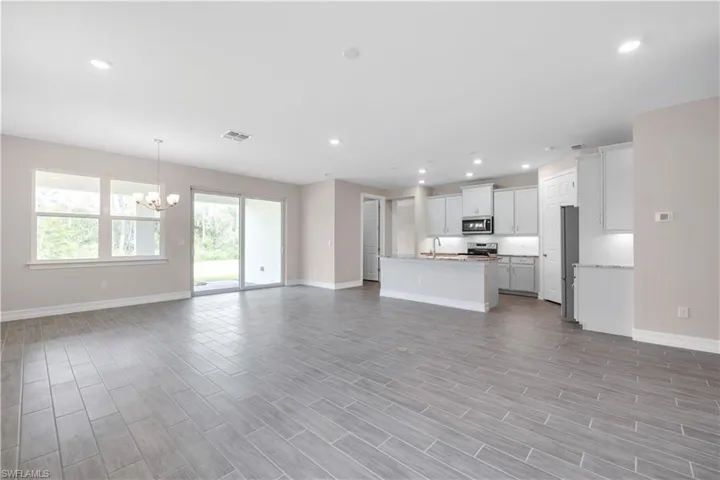 Unfurnished living room featuring light hardwood / wood-style floors, sink, and a chandelier