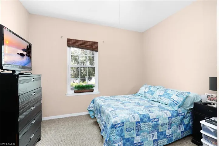 Bedroom with light colored carpet and lake view