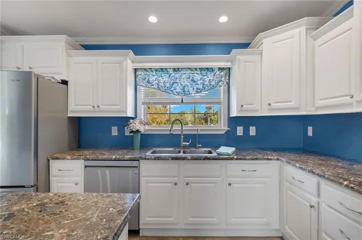 Kitchen featuring appliances with stainless steel finishes, white cabinetry, crown molding, and sink