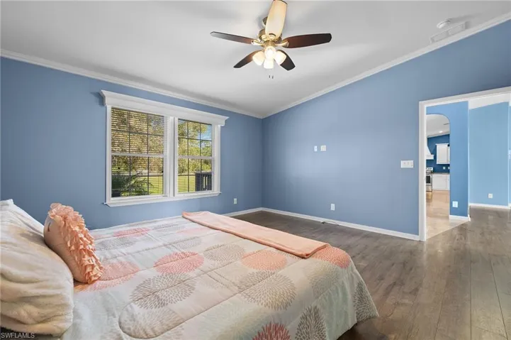 Bedroom with wood-type flooring, ceiling fan, and crown molding