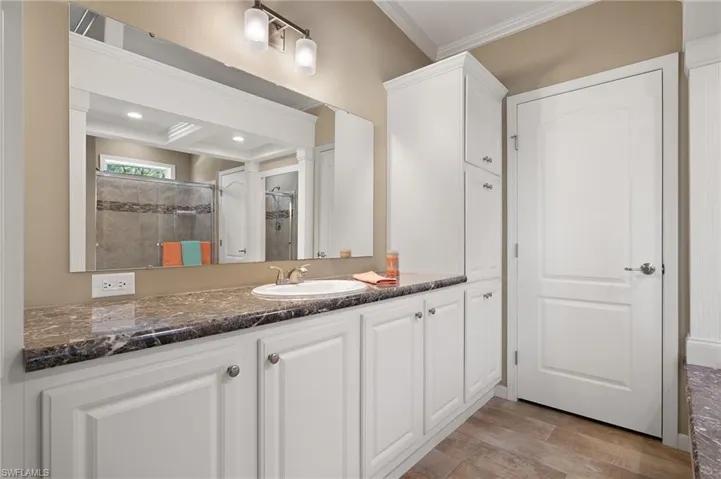 Bathroom featuring vanity, wood-type flooring, ornamental molding, and walk in shower
