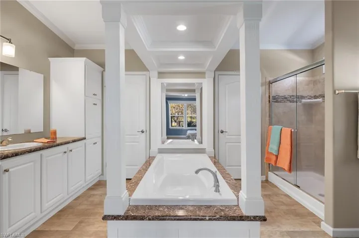 Bathroom with tile patterned floors, crown molding, a shower with door, and vanity