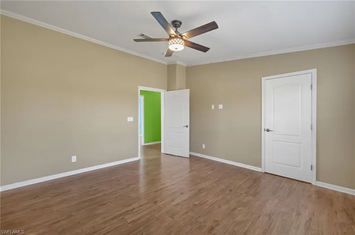 Spare room with ceiling fan, wood-type flooring, and ornamental molding
