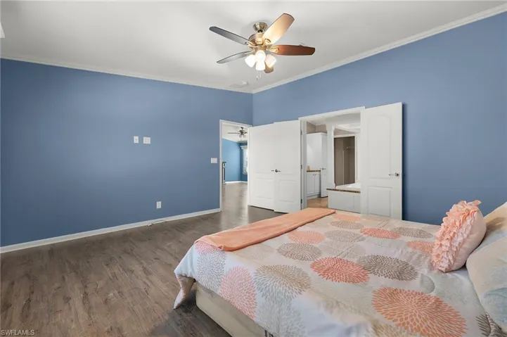 Bedroom with ceiling fan, dark hardwood / wood-style flooring, and crown molding