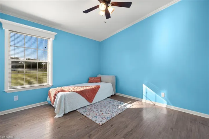 Bedroom with ceiling fan, dark hardwood / wood-style flooring, and ornamental molding