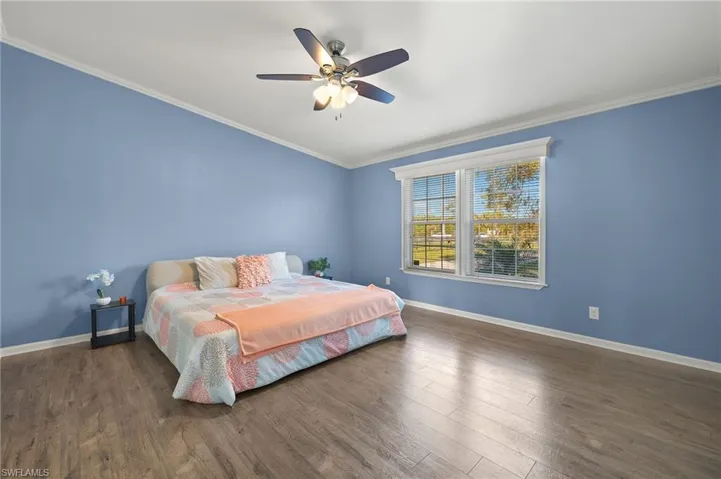 Bedroom with ceiling fan, dark hardwood / wood-style flooring, and crown molding
