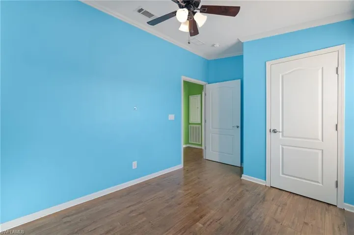 Unfurnished bedroom featuring dark hardwood / wood-style flooring, ceiling fan, and crown molding