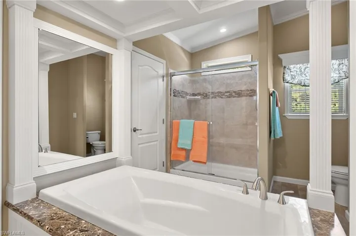 Bathroom with coffered ceiling, separate shower and tub, crown molding, beam ceiling, and toilet