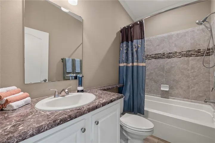 Full bathroom featuring shower / bath combo, vanity, toilet, and ornamental molding