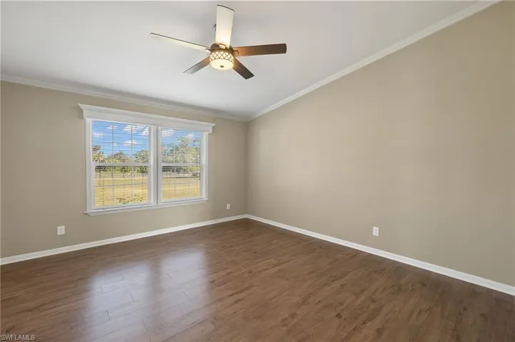 Unfurnished room with ceiling fan, dark hardwood / wood-style floors, and ornamental molding