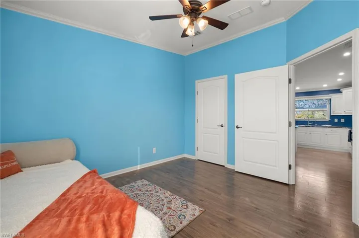 Bedroom featuring crown molding, ceiling fan, dark wood-type flooring, and sink