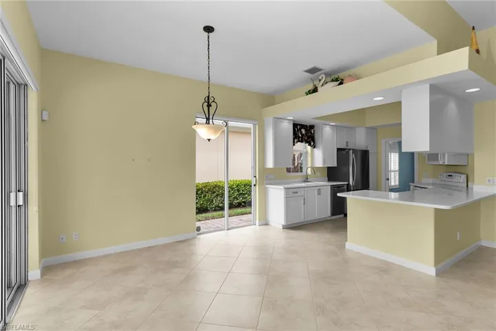 Kitchen featuring a peninsula, white cabinets, stainless steel appliances, a breakfast bar area, and decorative light fixtures