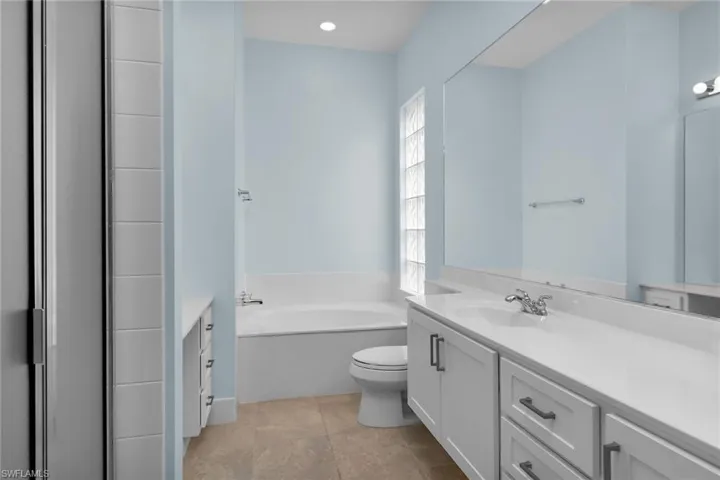 Full bathroom featuring vanity, a bath, and recessed lighting