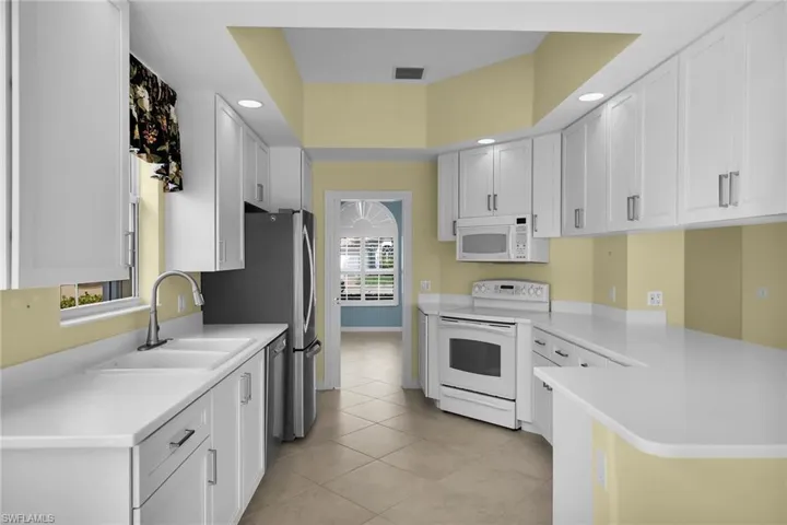 Kitchen with stainless steel appliances, white cabinets, light countertops, a peninsula, and recessed lighting