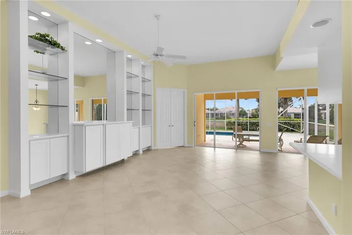 Empty room with built in features, ceiling fan, light tile patterned flooring, recessed lighting, and a high ceiling