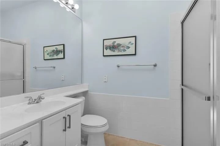 Full bathroom featuring a stall shower, vanity, tile walls, and wainscoting
