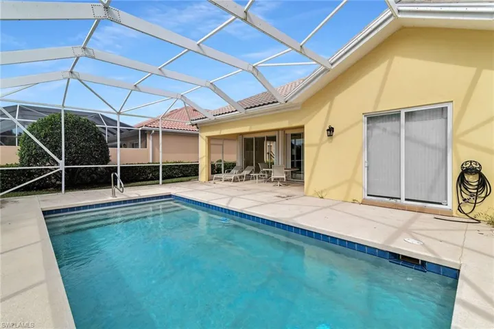 Outdoor pool with glass enclosure, a sunroom, and a patio area
