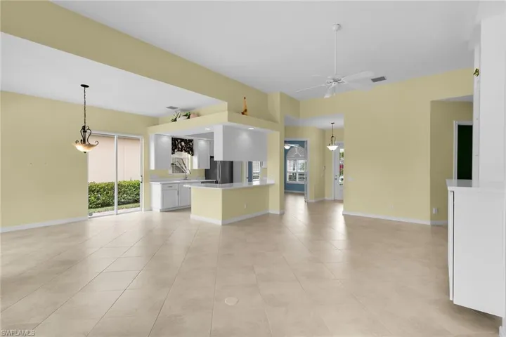 Kitchen featuring open floor plan, white cabinets, light countertops, and pendant lighting