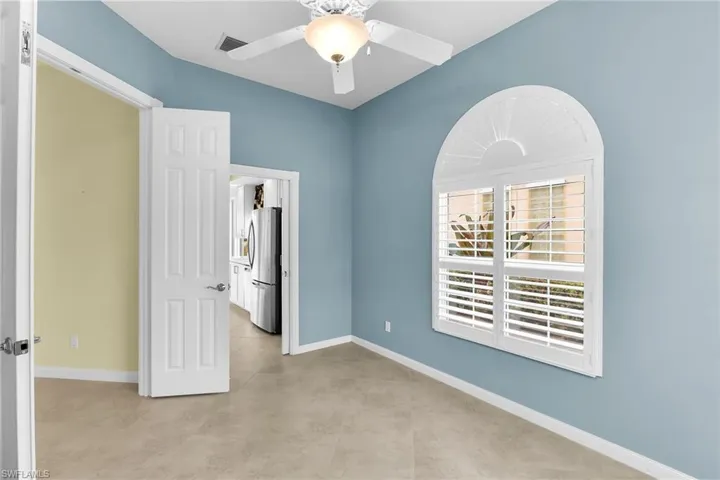 Unfurnished bedroom featuring freestanding refrigerator and a ceiling fan