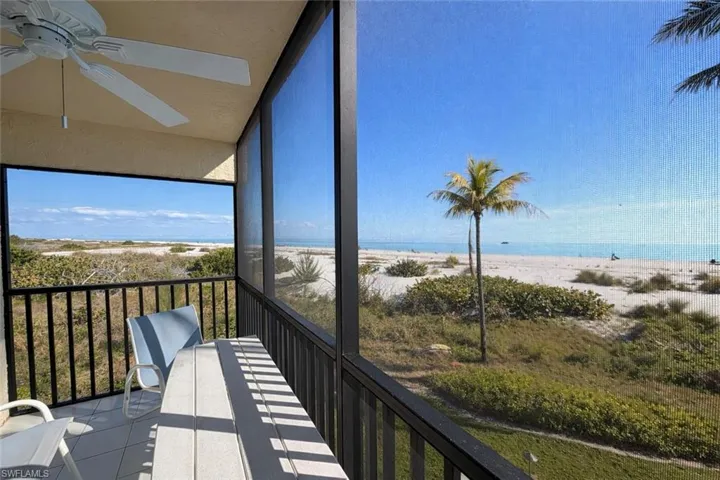 Unfurnished sunroom featuring view of water and beach, tile patterned flooring, and vaulted ceiling