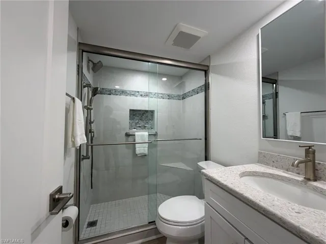 Bathroom with vanity, a shower stall, and a textured wall