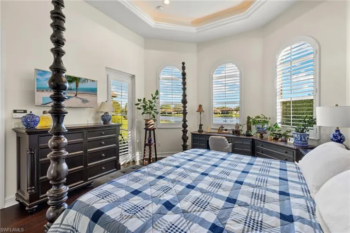 Bedroom with dark wood-type flooring, a tray ceiling, and multiple windows