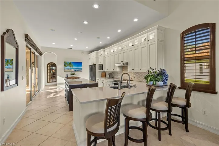 Kitchen featuring white cabinets, sink, tasteful backsplash, light tile patterned flooring, and kitchen peninsula