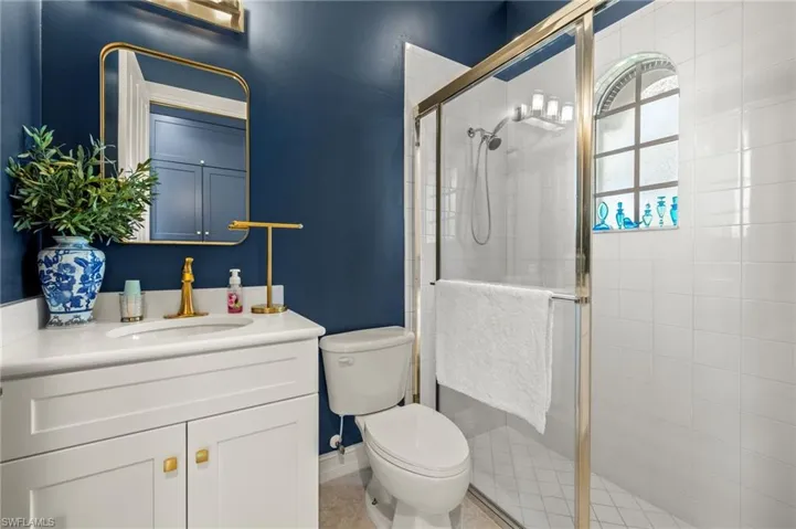Bathroom featuring tile patterned floors, vanity, a shower with shower door, and toilet