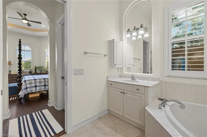 Bathroom featuring tiled bath, ceiling fan, hardwood / wood-style floors, and vanity