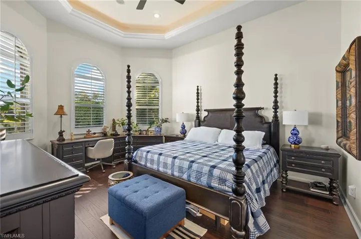 Bedroom with ceiling fan, dark hardwood / wood-style flooring, and multiple windows