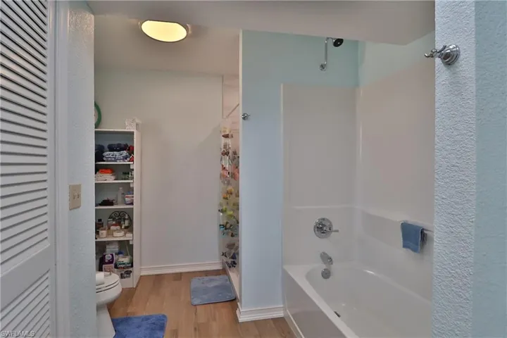 Bathroom with hardwood / wood-style floors, plus walk in shower, and toilet
