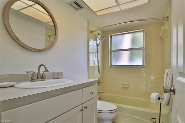 Full bathroom with tiled shower / bath combo, vanity, and toilet