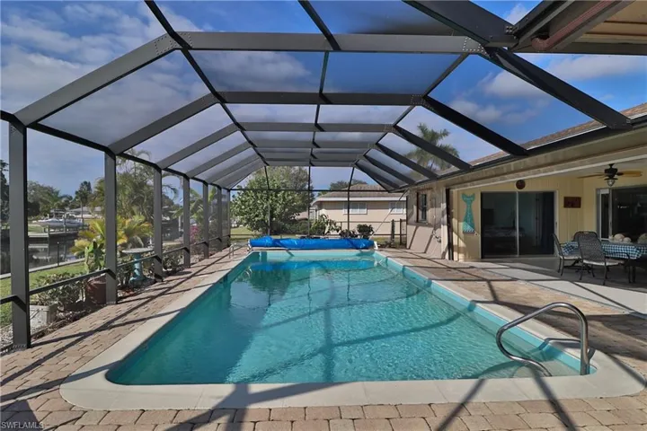 View of swimming pool with a patio, ceiling fan, and glass enclosure