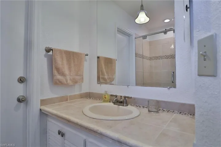 Bathroom featuring tiled shower and vanity