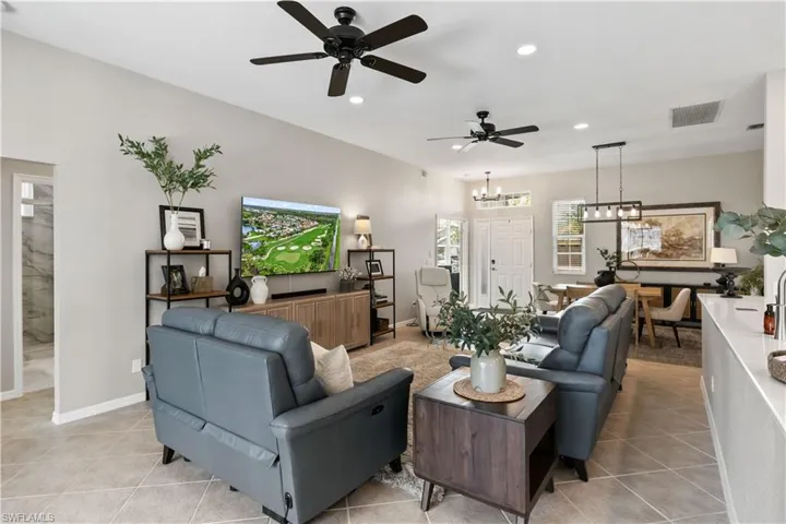 Tiled living room featuring ceiling fan with notable chandelier