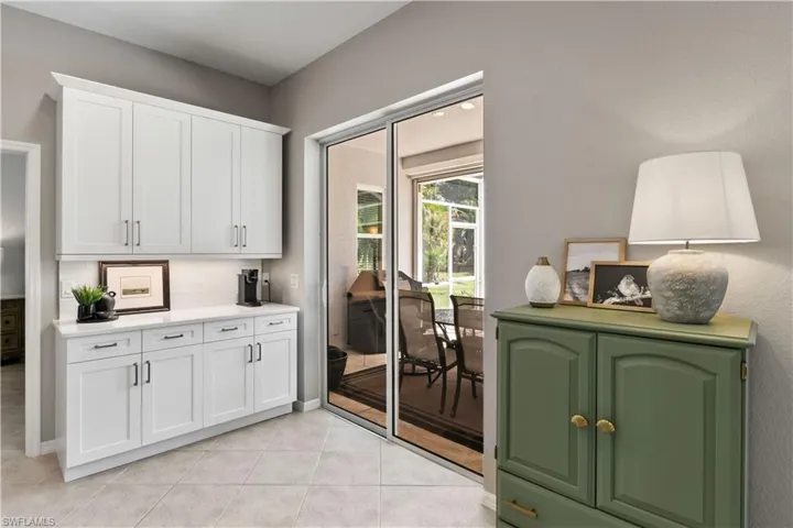 Kitchen featuring backsplash, light tile patterned floors, and white cabinets