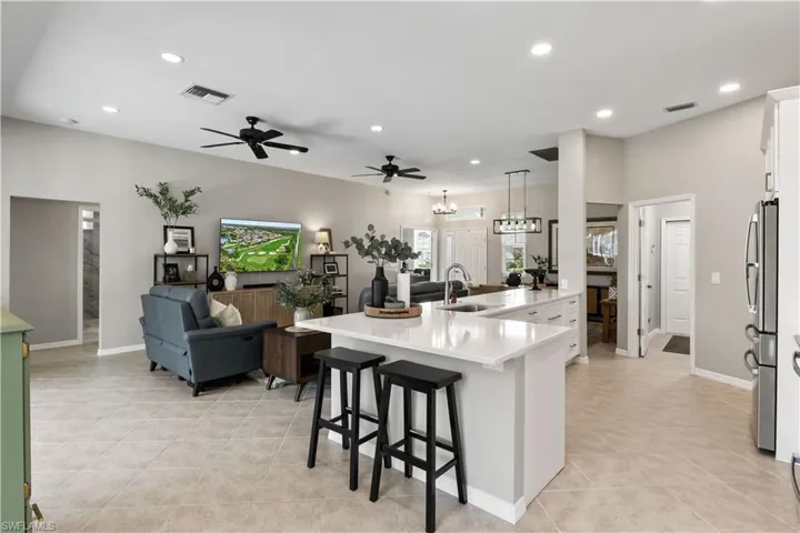Kitchen with stainless steel fridge, pendant lighting, a kitchen bar, sink, and white cabinetry