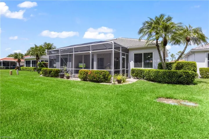 Back of property featuring a lanai and a lawn