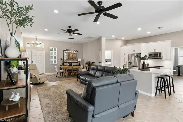 Tiled living room featuring ceiling fan with notable chandelier