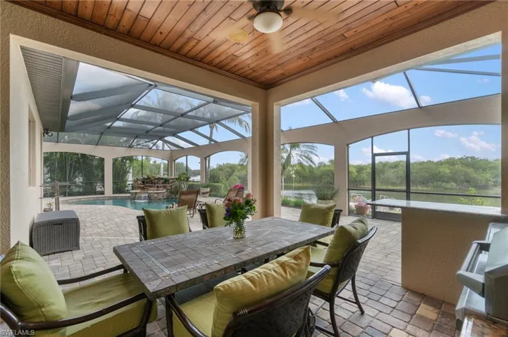Screened outdoor living area with wood-finish ceiling, ceiling fan, and paver flooring