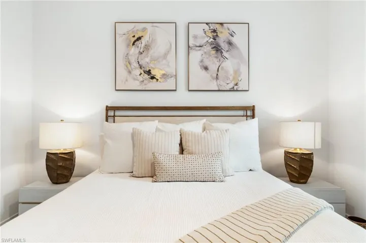 Bedroom featuring a prominent headboard, two coordinated bedside tables, and matching lamps with textured bases