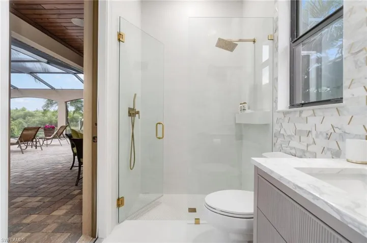 Modern bathroom featuring a glass-enclosed shower with gold-toned fixtures, a rain shower head, and a built-in shower niche
