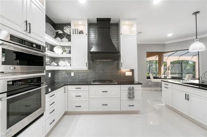 Contemporary kitchen featuring white cabinetry, dark countertops, and stainless steel built-in double ovens