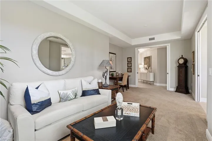 Carpeted living room with a tray ceiling and baseboards