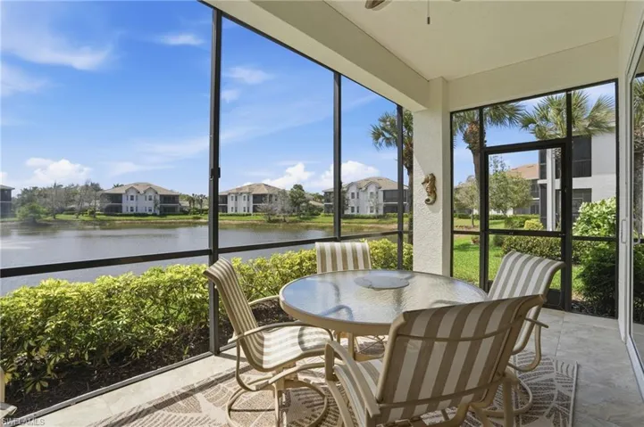 Sunroom featuring a water view, a residential view, a textured wall, and stone finish floors
