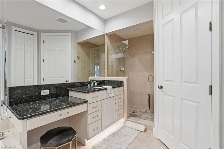Full bath with vanity, a closet, a stall shower, and light tile patterned floors