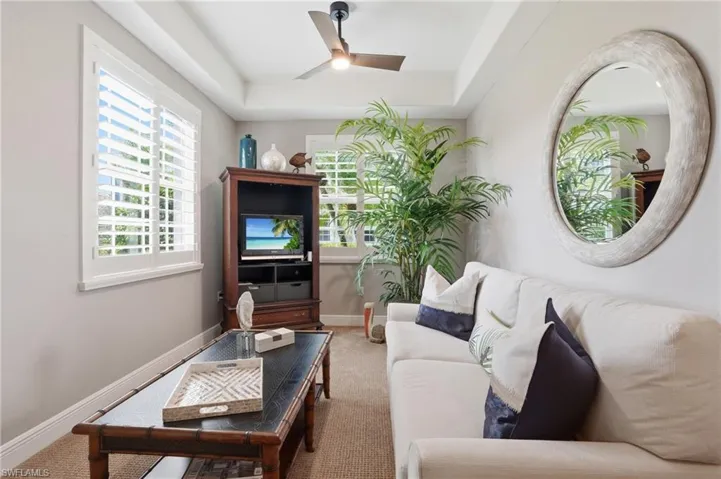Carpeted living area featuring a raised ceiling and ceiling fan
