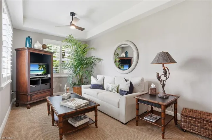 Carpeted living room featuring a tray ceiling and ceiling fan