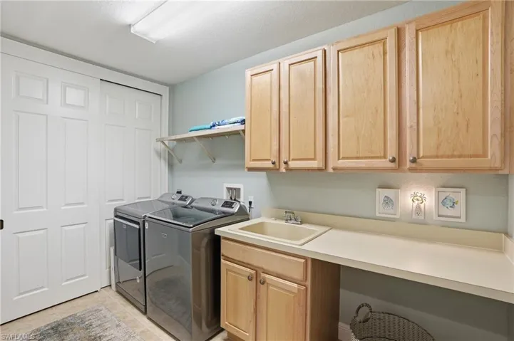 Laundry area featuring washer and dryer, cabinet space, and light tile patterned floors